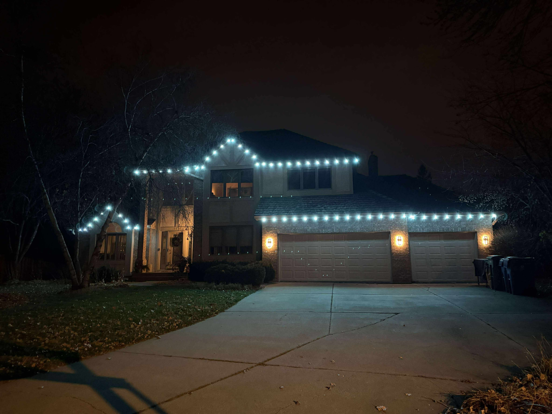 Two-story home outlined in crisp white permanent LED lighting